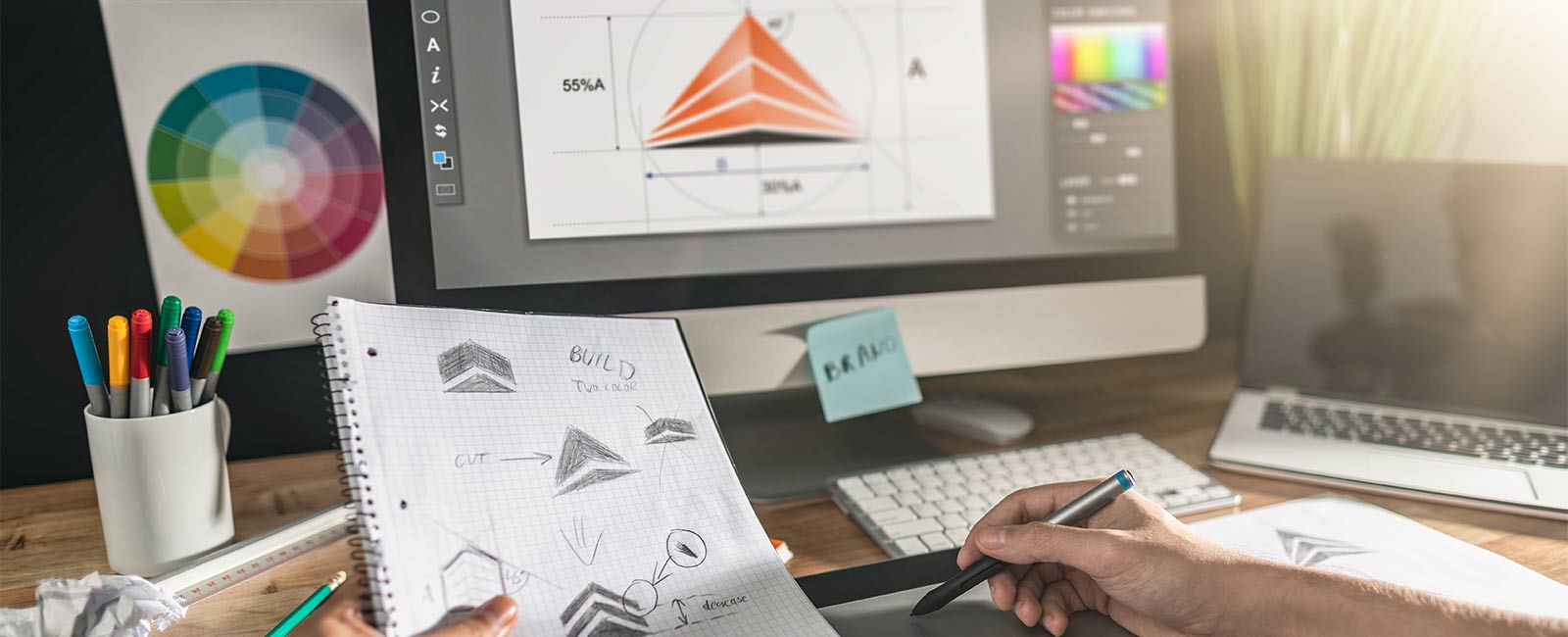 A logo designer working on a wacom tablet drawing a logo design on a computer.